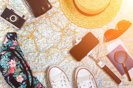 Accessories for travel. Passport, hat, smart phone and travel map. Top view. Holidays and tourism concept. Copy space. Still life. Flat lay. Sun flare