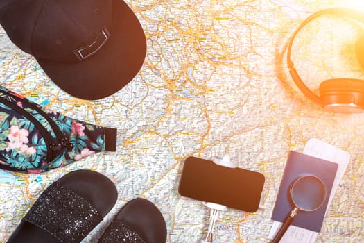 Accessories for travel. Passport, hat, smart phone and travel map. Top view. Holidays and tourism concept. Copy space. Still life. Flat lay. Sun flare