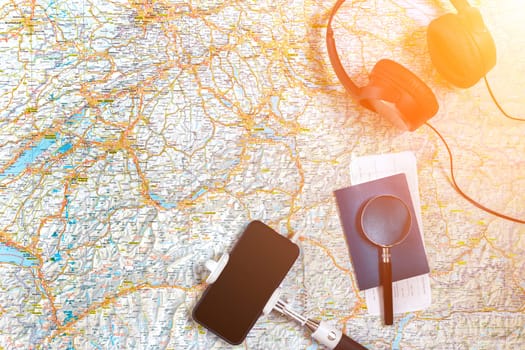 Accessories for travel. Passport, headphones, smart phone and travel map. Top view. Holidays and tourism concept. Copy space. Still life. Flat lay. Sun flare