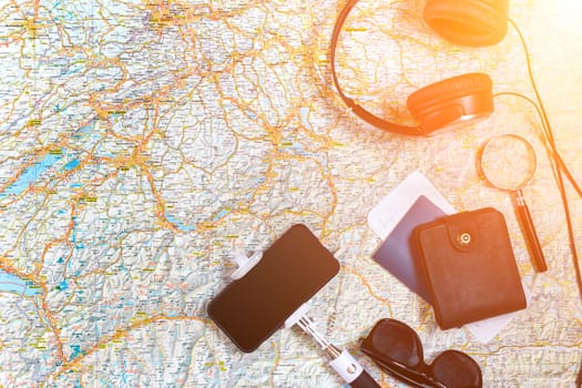 Accessories for travel. Passport, headphones, smart phone and travel map. Top view. Holidays and tourism concept. Copy space. Still life. Flat lay. Sun flare