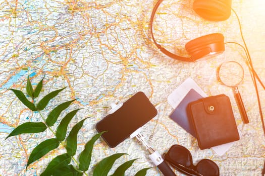 Accessories for travel. Passport, headphones, smart phone and travel map. Top view. Holidays and tourism concept. Copy space. Still life. Flat lay. Sun flare