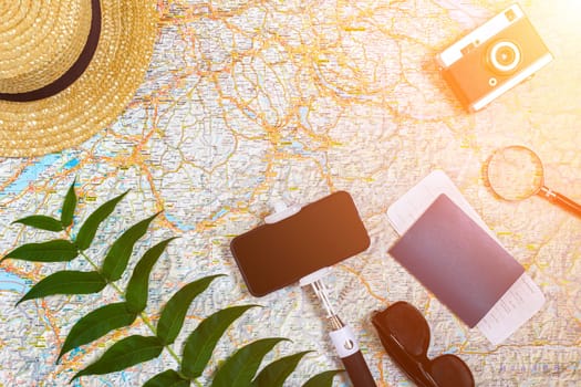 Accessories for travel. Passport, hat, smart phone and travel map. Top view. Holidays and tourism concept. Copy space. Still life. Flat lay. Sun flare