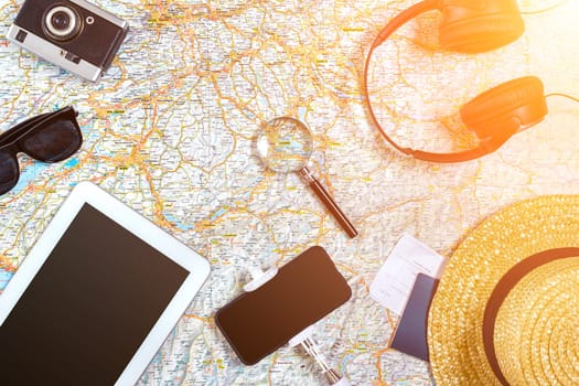 Accessories for travel. Passport, photo camera, smart phone and travel map. Top view. Holidays and tourism concept. Copy space. Still life. Flat lay. Sun flare
