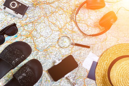 Accessories for travel. Passport, photo camera, smart phone and travel map. Top view. Holidays and tourism concept. Copy space. Still life. Flat lay. Sun flare