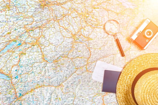 Map of roads with a vintage camera, passport, sunglasses. View from above. The concept of travel. Copy space. Flat lay. Sun flare