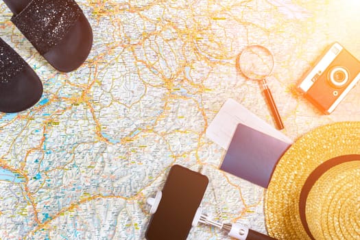 Accessories for travel. Passport, photo camera, smart phone and travel map. Top view. Holidays and tourism concept. Copy space. Still life. Flat lay. Sun flare