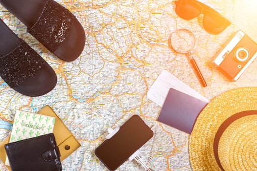Accessories for travel. Passport, photo camera, smart phone and travel map. Top view. Holidays and tourism concept. Copy space. Still life. Flat lay. Sun flare