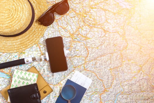 Accessories for travel. Passport, hat, smart phone and travel map. Top view. Holidays and tourism concept. Copy space. Still life. Flat lay. Sun flare