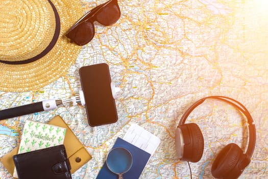 Accessories for travel. Passport, hat, smart phone and travel map. Top view. Holidays and tourism concept. Copy space. Still life. Flat lay. Sun flare
