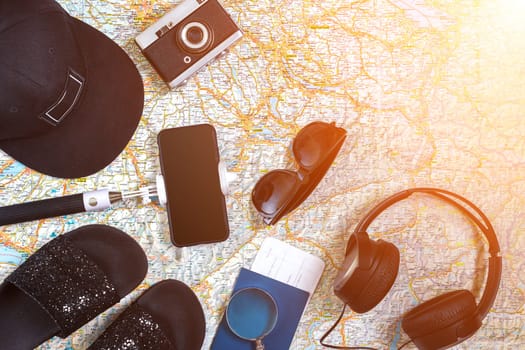 Accessories for travel. Passport, photo camera, smart phone and travel map. Top view. Holidays and tourism concept. Copy space. Still life. Flat lay. Sun flare