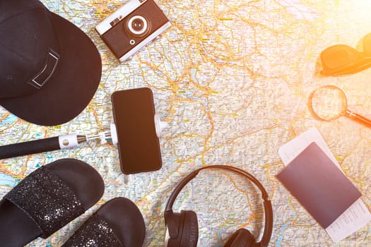 Accessories for travel. Passport, photo camera, smart phone and travel map. Top view. Holidays and tourism concept. Copy space. Still life. Flat lay. Sun flare