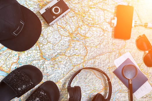 Accessories for travel. Passport, photo camera, smart phone and travel map. Top view. Holidays and tourism concept. Copy space. Still life. Flat lay. Sun flare