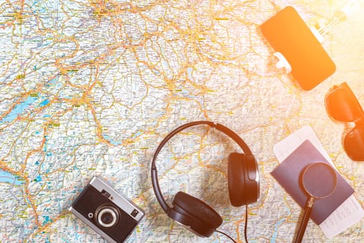 Accessories for travel. Passport, photo camera, smart phone and travel map. Top view. Holidays and tourism concept. Copy space. Still life. Flat lay. Sun flare
