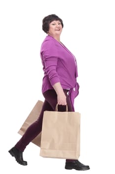 casual elderly woman with shopping bags striding forward. isolated on a white background.