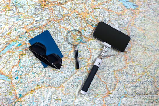 Travel accessories set on the map background: smart, passport and sunglasses. Top view point. Flat lay. Still life