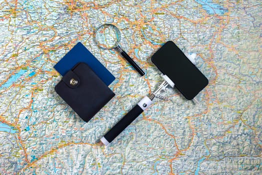 Travel accessories set on the map background: smart, passport and selfish stick. Top view point. Flat lay. Still life. Copy space