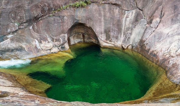 Crystal clear water from a green river flows into a breathtaking hole in the rock. A must-visit spot for a refreshing swim and Instagram-worthy photos.