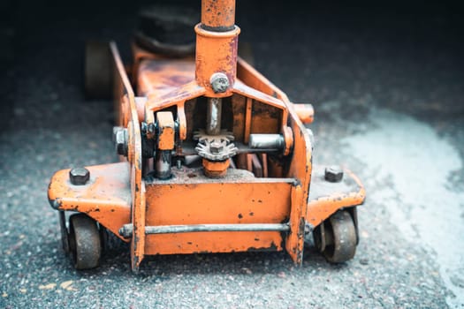 gear mechanism of a large professional automotive hydraulic floor jack. regular maintenance of the car. close-up of a car jack. Orange hydraulic floor jack for repair. Service