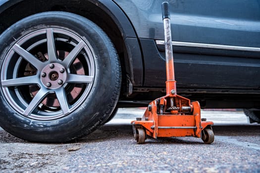 the car is jacked using an automobile hydraulic jack to replace the wheels. regular maintenance of the car. Orange hydraulic jack for floor repair. Service