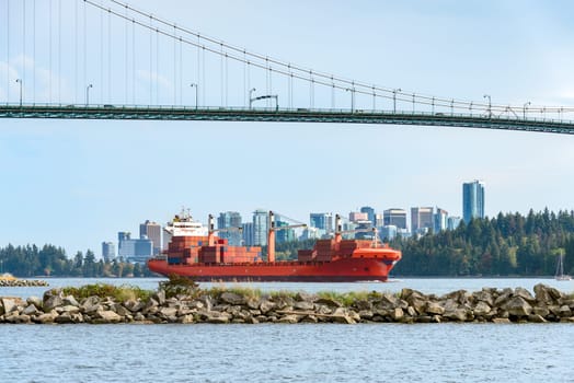 Container cargo liner in Vancouver harbor going fairway under Lions Gate bridge.