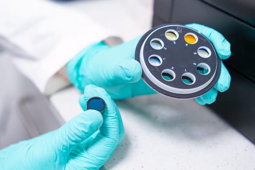 The scientist changes UV filters intended for microbiological analysis using a spectrophotometer.