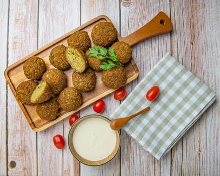 Falafel balls on a wooden cutting board and tahini sauce, High quality photo