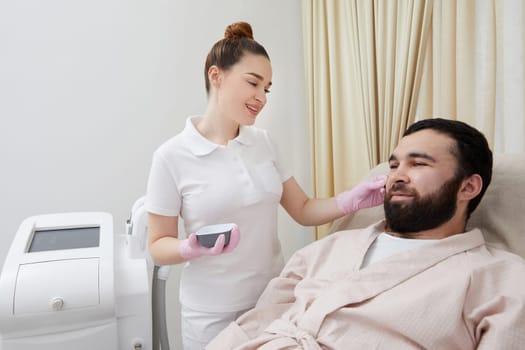 Bearded man getting laser facial treatment by professional cosmetologist in a beauty clinic. Healthy man lifestyle concept