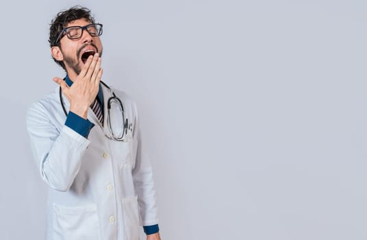 Young sleepy doctor yawning on isolated background. Tired of working doctor concept, Tired and sleepy doctor isolated