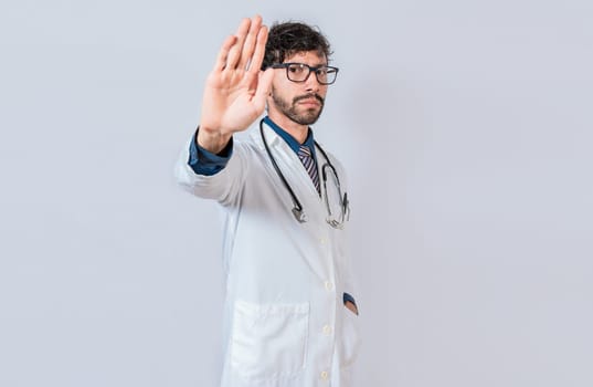 Serious doctor making stop gesture on isolated background, Young doctor making stop gesture with palm of hand