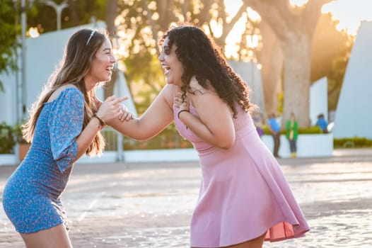 Happy female friends laughing in the street. Concept of happy female friends chatting in the street, Two happy girls laughing in the street