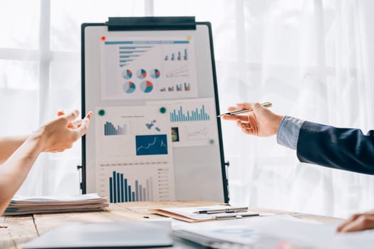 portrait of young asian business team presents business profits to colleagues at meeting, explaining business turn over on flipchart to coworkers in office with using tablet