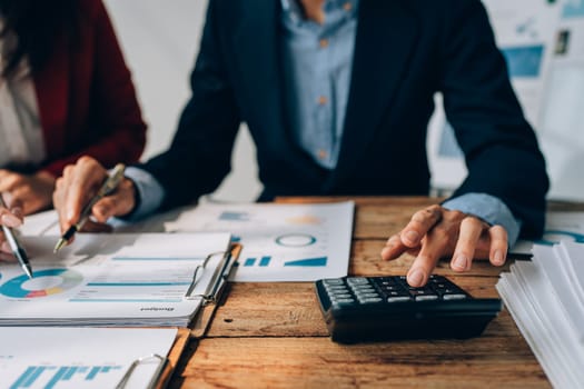 Two business people meeting to talking or discuss marketing work in workplace using paperwork, calculator, computer to work.