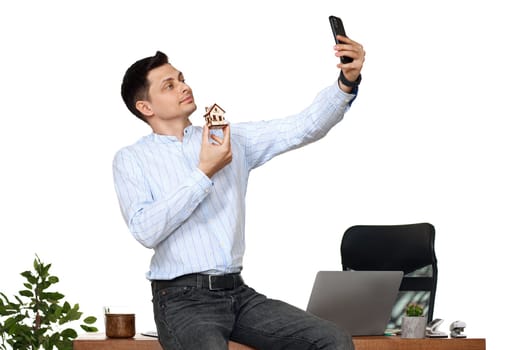 caucasian businessman holding toy house and taking selfie in the office. real estate insurance