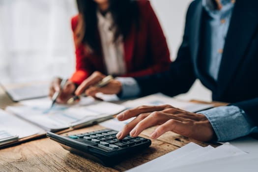 Two business people meeting to talking or discuss marketing work in workplace using paperwork, calculator, computer to work.