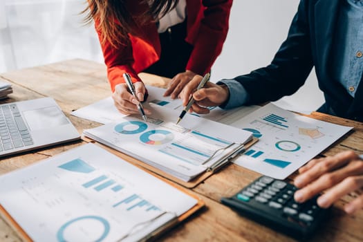 Two business people meeting to talking or discuss marketing work in workplace using paperwork, calculator, computer to work.