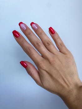 Red nail professional manicure, woman hand, beige sleeve. High quality photo