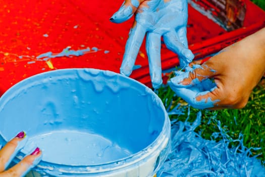 blue paint bucket and red plastic tray. two hands full of blue paint. High quality photo