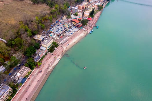aerial drone shot of blue water of river ganga stretching into distance with steps stairs on the ghat bank of the river with temple and houses in India