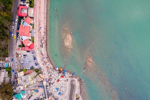 aerial drone shot showing rafts for water adventure sports on the blue waters of ganga river in rishikesh with people watching from the ghats on the riverbank in India