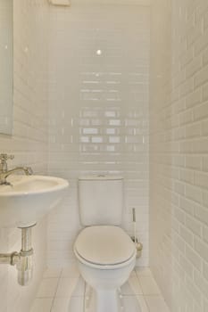 a small bathroom with white tiles on the walls and floor, along with a toilet in the center of the room