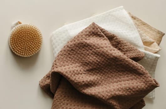 Towels and a washcloth brush lie on a beige surface.