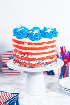 Decorating chocolate cake with white, red, and blue buttercream frosting for July 4th celebration.