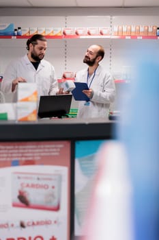 Drugstore colleagues standing at counter desk doing medication and pharmaceutical products inventory in pharmacy. Employees is trained to recognize and address any potential drug interactions