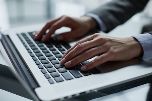 man's hands typing on laptop keyboard in interior