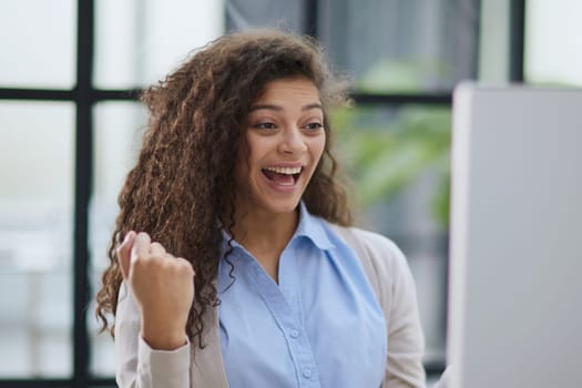 expressive young woman open mouth checking discounts for online shopping sitting at desktop .