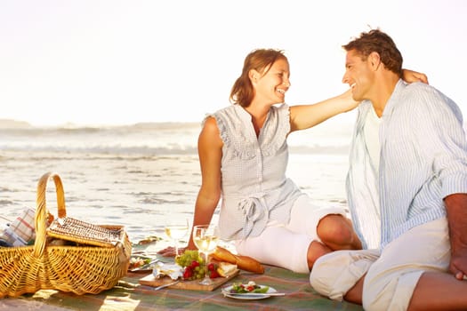 Romantic picnic at sunset. A loving mature couple enjoying a romantic picnic on the beach together