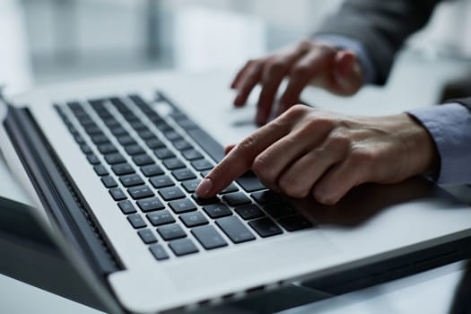 man's hands typing on laptop keyboard in interior