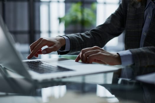 man's hands typing on laptop keyboard in interior