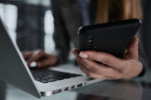 male hands hold a smartphone and use it for online shopping while looking at a laptop