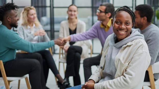 Successful African American manager sitting in front of her colleagues